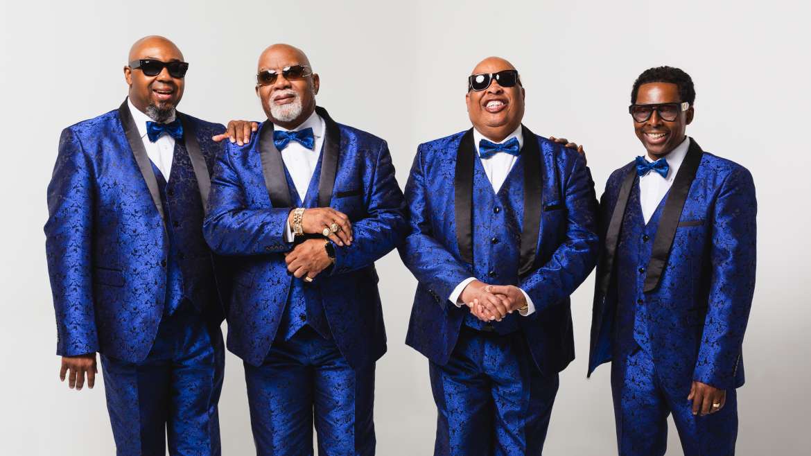 Gospel quartet Blind Boys of Alabama standing side by side in a friendly manner, wearing blue 3-piece suits and bowties