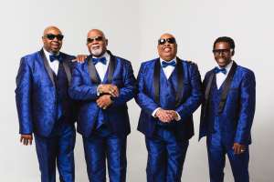 Gospel quartet Blind Boys of Alabama standing side by side in a friendly manner, wearing blue 3-piece suits and bowties