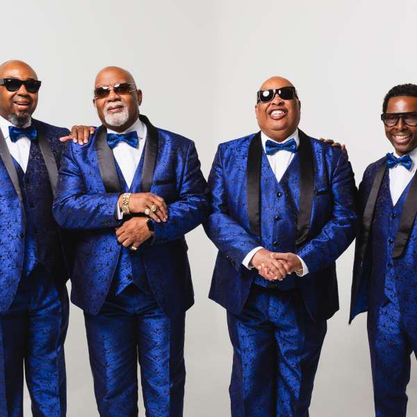 Gospel quartet Blind Boys of Alabama standing side by side in a friendly manner, wearing blue 3-piece suits and bowties