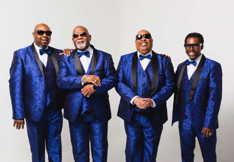 Gospel quartet Blind Boys of Alabama standing side by side in a friendly manner, wearing blue 3-piece suits and bowties
